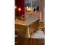 Feestelijke eettafel met gouden tafelkleed, rode kaarsen en kerstdecoraties.