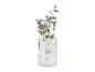 Gegroefde glazen vaas met eucalyptus en paarse bloemen.