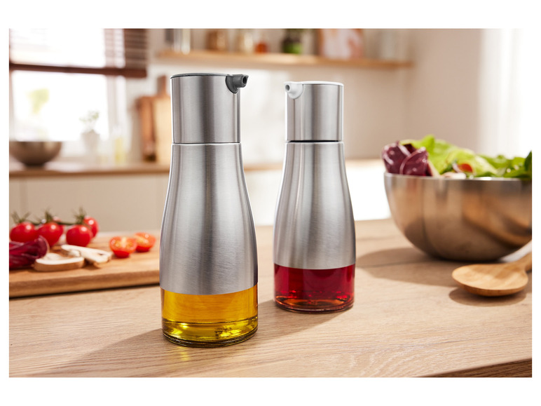 Twee stalen olieverspreiders met olie en azijn op een houten tafel