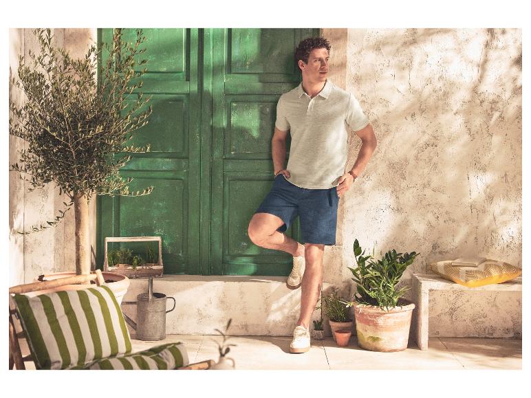 Man in ESMARA MEN piqué poloshirt en short, staand voor een groene deur.