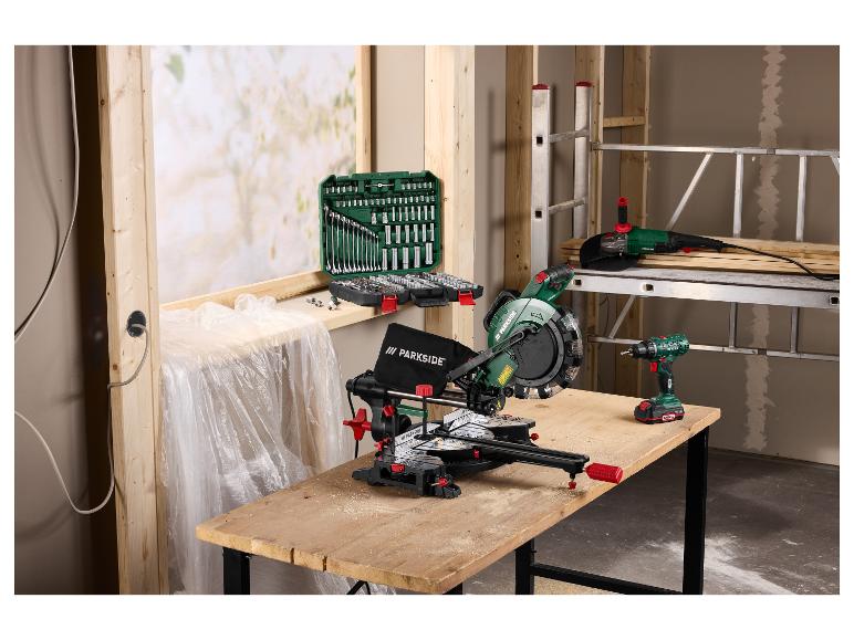 Afkortzaag, haakse slijper en boormachine op een werkbank met doppenset in een werkplaats.