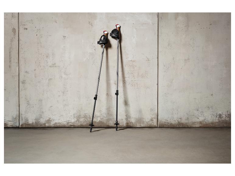 Twee wandelstokken van het merk CRIVIT tegen een betonnen muur.