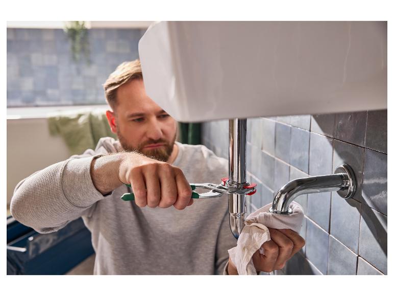 Een man repareert de afvoer van een wastafel met een tang.