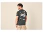 Man van achteren in donkergroen T-shirt met bergprint en beige shorts.