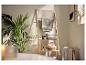 Badkamer met een houten handdoekenrek, groene handdoeken en een plant, wat een natuurlijke, spa-achtige sfeer creëert.