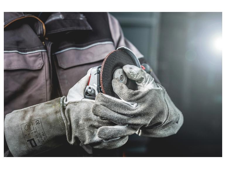 Handen in beschermende handschoenen houden een haakse slijper met slijpschijf vast.