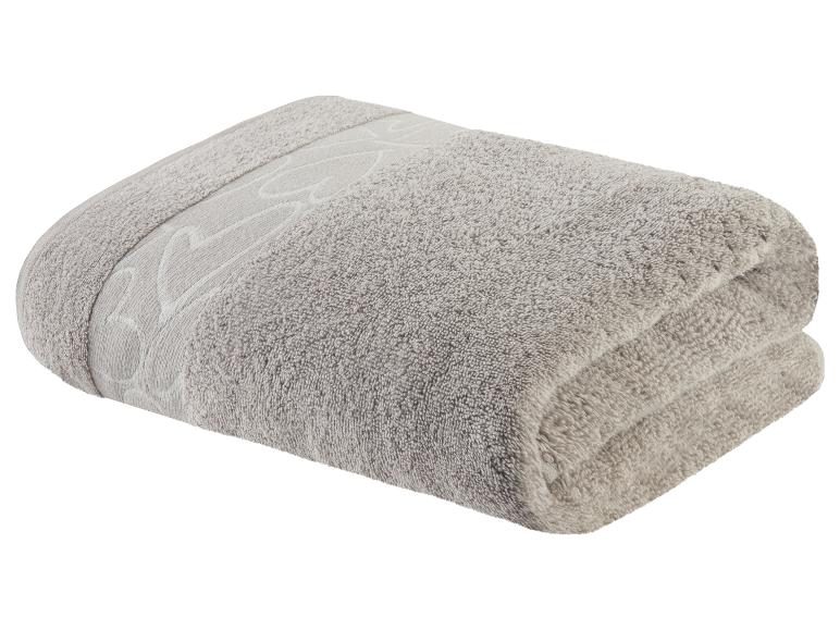 Een gevouwen, grijze handdoek met een geborduurd ontwerp.