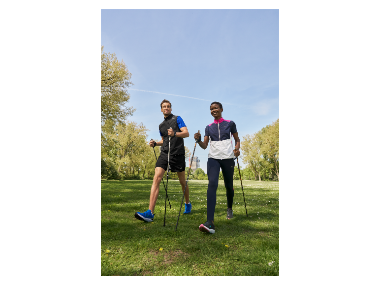 Twee personen nordic walken in een park.