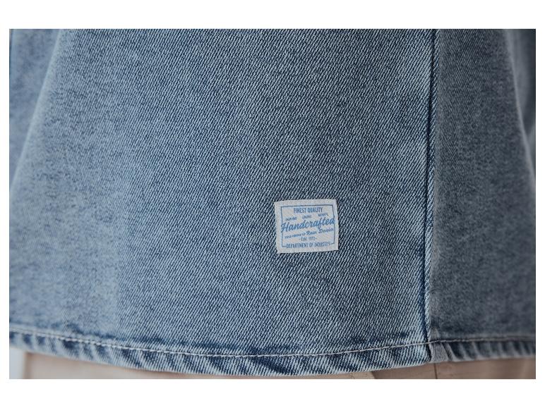 Een close-up van denim stof met een label dat 'Handcrafted Raw Denim' zegt.