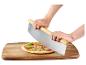 Handen snijden pizza met een grote pizzames op een houten plank.