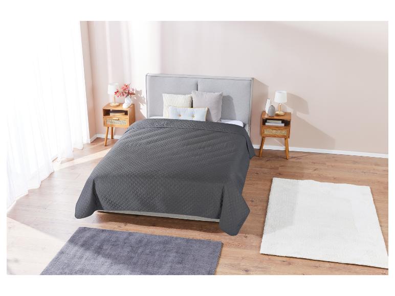 Grijs gestikt dekbed en zachte tapijten in een moderne slaapkamer.