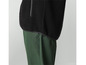 Een zwart fleece jack met een groene broek.