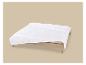 Wit gewatteerd dekbed op een houten bed met een beige achtergrond.