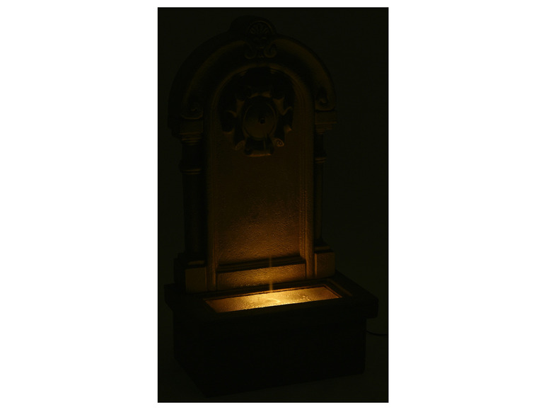 Een stenen fontein met verlichting voor in de tuin.