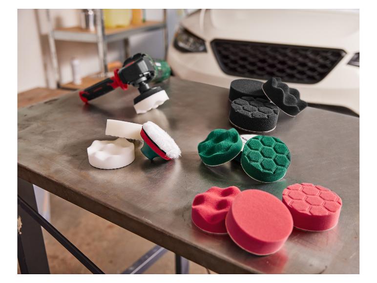 Verschillende polijstpads en een polijstmachine voor auto's op een metalen tafel.