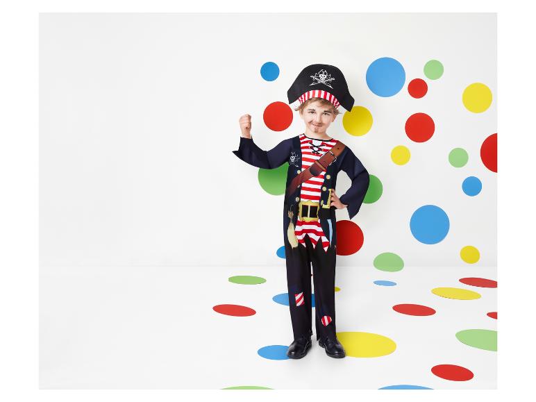 Een jongen in een piratenkostuum staat voor een achtergrond met gekleurde stippen.