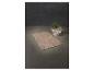 Beige badmat en handdoeken in een witte mand met een groene plant