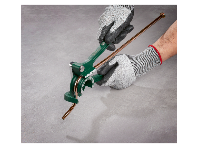 Gehandschoende handen gebruiken een gereedschap om koperen buizen te buigen.