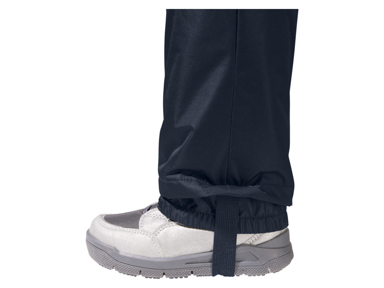 Een close-up van de onderkant van een blauwe broek met een witte schoen.