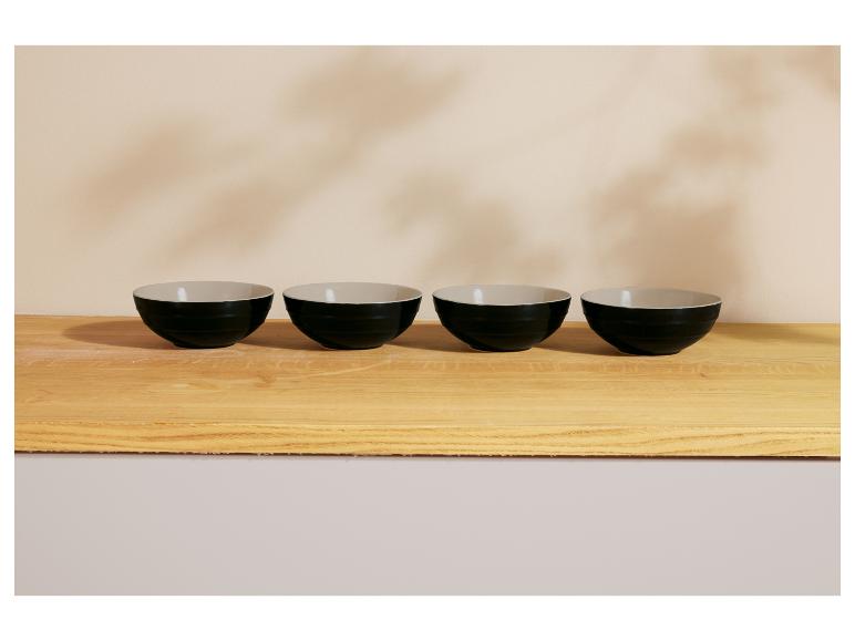 Vier zwarte kommen op een houten aanrechtblad.