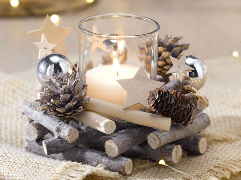 Een kerstkaarshouder met sterren, dennenappels en takken.