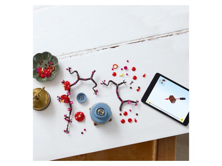Kersenbloesem bouwstukken en tablet met instructies op een witte tafel.