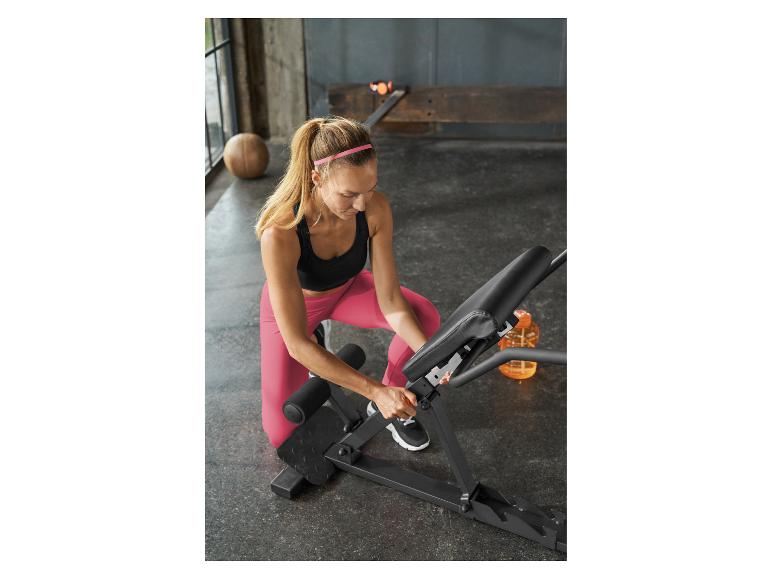 Vrouw stelt een halterbank in een sportschool af.