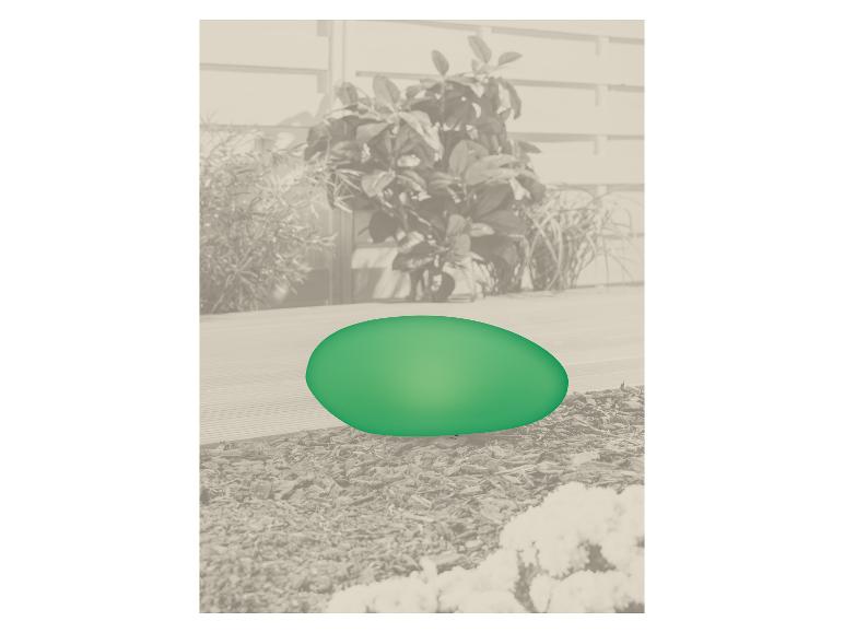 Groen decoratief ei op een terras met planten op de achtergrond.