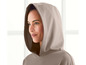 Een vrouw draagt een beige hoodie met capuchon.
