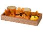Herfst houten dienblad met twee oranje glazen kandelaars, esdoornbladeren en pompoenen.