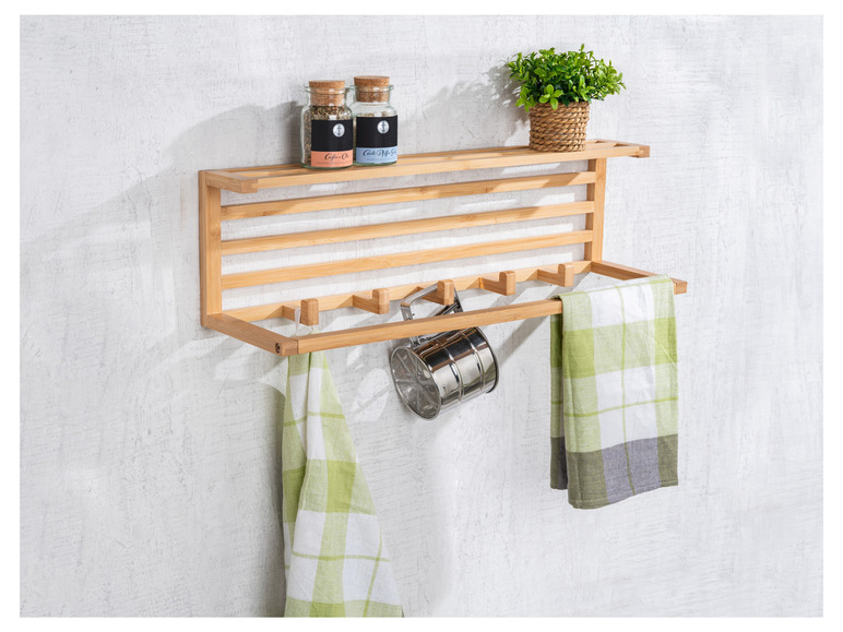 Een houten wandrek met handdoeken, een zeef en specerijenpotjes.