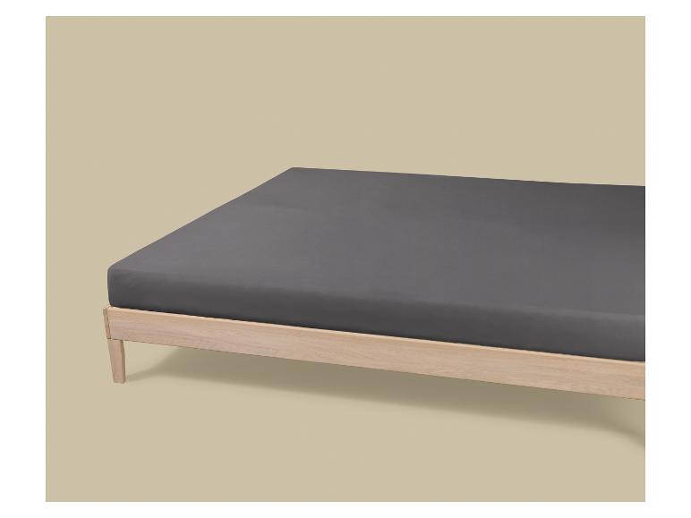 Houten bed met een donkergrijs matras op een beige achtergrond.