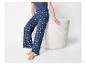 Vrouw in donkerblauwe pyjamabroek met madeliefjesprint en bijpassend T-shirt, zittend.