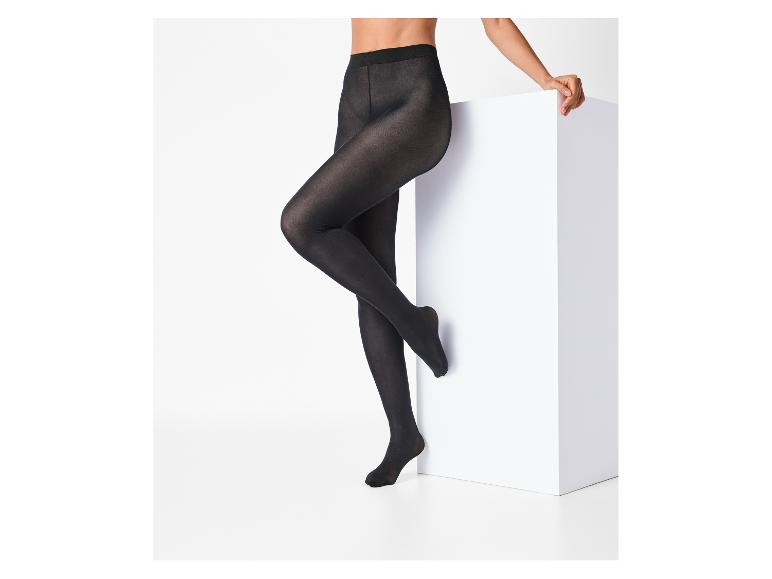 Vrouw in zwarte panty poseert bij een wit blok.