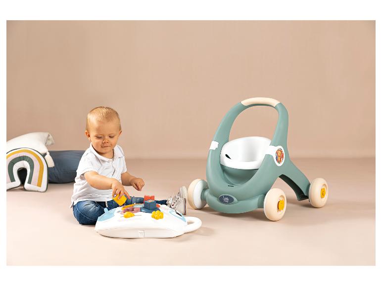 Baby speelt met een activiteitenbord en een Little Smoby loopwagen op de achtergrond.