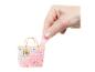 Een hand trekt een roze, glitterachtige substantie uit een doorzichtige minitas versierd met hartjes en gouden letters.
