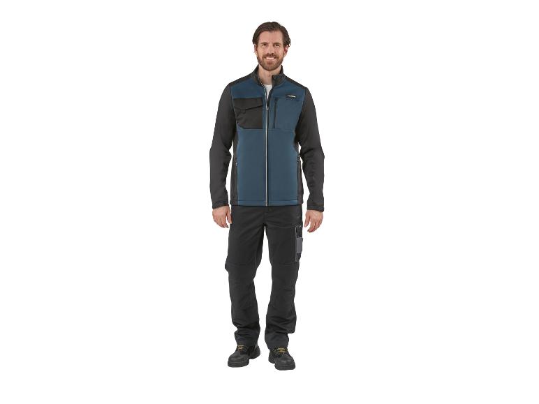 Man in tweekleurige werkjas en broek, glimlachend.