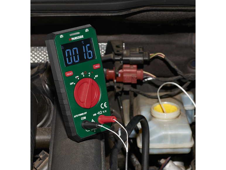 Een multimeter meet de temperatuur in de motorruimte van een auto, met 16 graden Celsius.