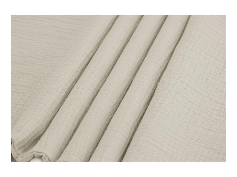 Lichtbeige mousseline stof, zacht gevouwen.