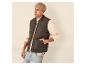 Man in bruin gewatteerd vest, beige sweatshirt, jeans en gebreide muts.