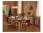 Elegant gedekte kersttafel met houten stoelen en feestelijke decoraties.