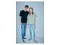 Twee jonge mensen dragen casual T-shirts en jeans met sneakers tegen een lichtblauwe achtergrond.