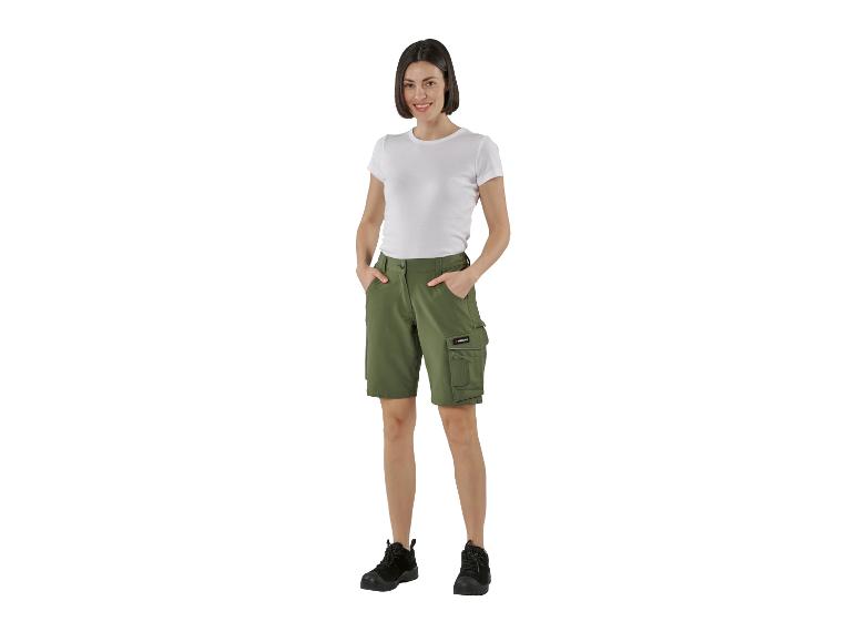 Lachende vrouw in wit T-shirt en olijfgroene cargoshorts met zwarte laarzen.