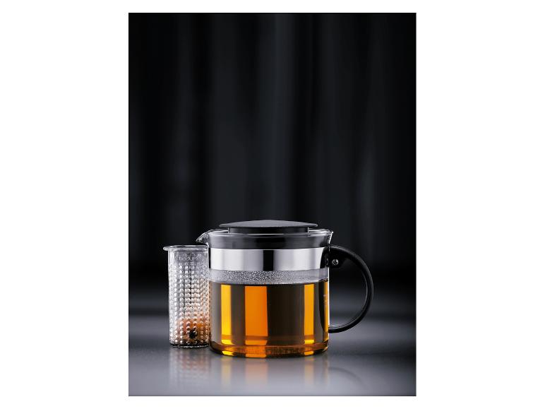 Glazen theepot met theezeef, gevuld met amberkleurige thee.