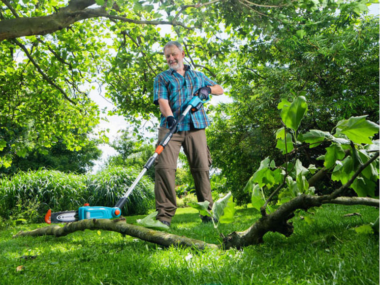 Een man gebruikt een Gardena kettingzaag om een tak te snoeien.