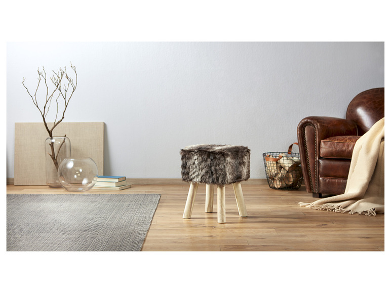 Een faux fur poef op houten poten in een modern interieur.