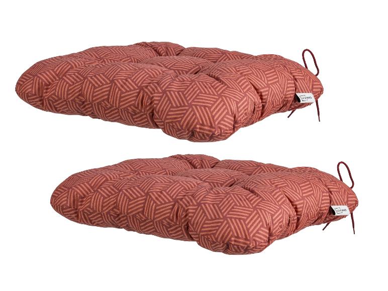 Twee rode zitkussens met een geometrisch patroon en strikbanden.