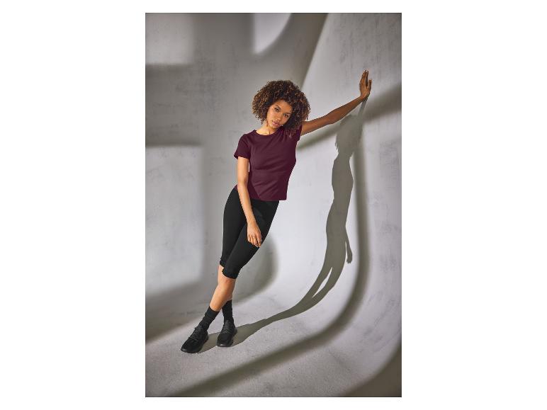 Vrouw in zwarte ESMARA® capri-legging en bordeauxrood T-shirt.