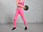 Vrouw in roze sportlegging met zwarte sneakers en een medicijnbal.