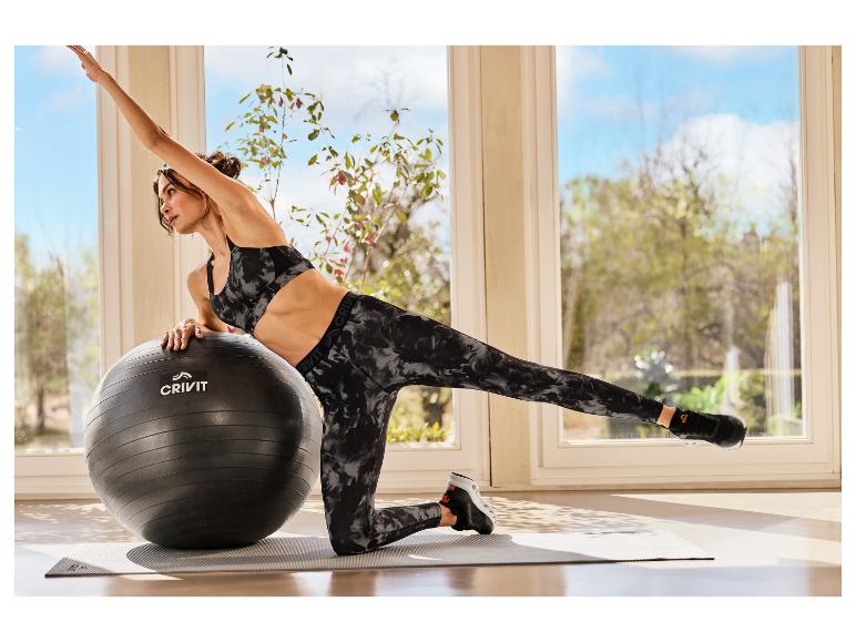 Vrouw in CRIVIT sportlegging traint met een fitnessbal.